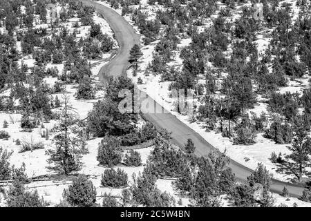 Blick auf eine Straße, die sich durch die Landschaft von New Mexico schlängelt, mit Schnee auf dem Boden Stockfoto