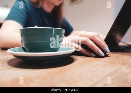 Seitenansicht einer Frau, die einen Laptop mit einer Tasse Kaffee benutzt Stockfoto