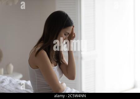 Unglücklich ungesunde junge Frau, die den Kopf berührt, unter Kopfschmerzen leidet Stockfoto