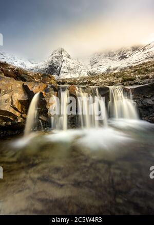 Fairy Pools Wasserfall auf der Isle of Skye mit schneebedeckten Bergen. Stockfoto