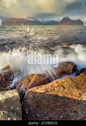 Krachende Wellen an der Küste der inneren Hebriden mit dramatischen winterstürmischen Regenwolken am Himmel. Aufgenommen in Elgol auf der Isle of Skye. Stockfoto