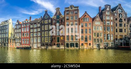 Panoramablick auf typisch holländische Häuser am Amsterdamer Kanal Damrak an sonnigen Tagen, Niederlande. Hochwertige Fotos Stockfoto