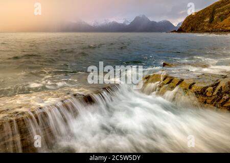 Krachende Wellen an der Küste der inneren Hebriden mit dramatischen winterstürmischen Regenwolken am Himmel. Aufgenommen in Elgol auf der Isle of Skye. Stockfoto