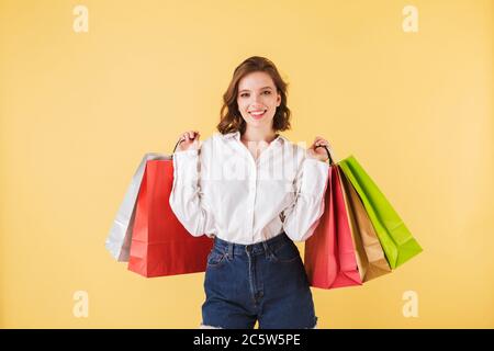 Portrait einer schönen lächelnden Dame, die mit bunten Einkaufstaschen in den Händen steht und freudig in der Kamera auf rosa Hintergrund schaut. Hübsche Frau Stockfoto