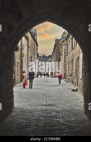 Dinan, Bretagne, Frankreich. Alte gepflasterte Straße, die zur Porte de Saint Malo und den befestigten Mauern führt. Stockfoto