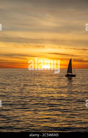 Ein silhouetted Segelschiff auf dem Ozean, gegen einen Sonnenuntergang Himmel Stockfoto