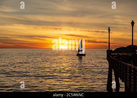 Der Pier am Redondo Beach in Kalifornien und ein silhouetted Segelboot, bei Sonnenuntergang Stockfoto