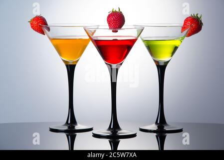 Farbige Getränke in martinigläsern mit Erdbeeren, Cocktails mit Likören Stockfoto