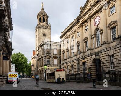 Ein Deliveroo Takeaway Radfahrer fährt an einem Burger van auf der Corn Street vor dem großen Georgian Corn Exchange Gebäude und All Saints Church in geparkt Stockfoto