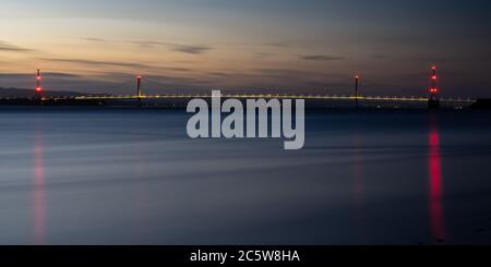 Ein Nachglühen des Sonnenuntergangs hängt über der Severn Bridge und dem Flussmündungsgebiet von Severn in Gloucestershire. Stockfoto