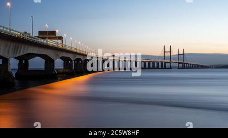 Die zweite Severn Crossing Brücke, die die Autobahn M4 zwischen England und Wales führt, wird bei Einbruch der Dunkelheit von Straßenlaternen und den Spuren des vorbeifahrenden Verkehrs beleuchtet. Stockfoto