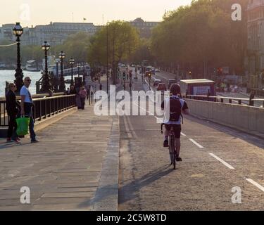 Radfahrer, Fußgänger und Verkehr ziehen an einem sonnigen Abend in London entlang des Themse-Damms. Stockfoto