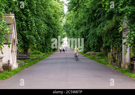 London, England, Großbritannien - 18. Juni 2013: Radfahrer und Fußgänger reisen durch den bewaldeten Brompton Friedhof im Westen Londons. Stockfoto