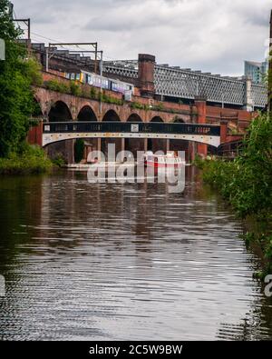 Ein Zug der Klasse 142 "Pacer" fährt auf einem viktorianischen Backsteinviadukt über dem Bridgewater Canal im Castlefield Basin in Manchester. Stockfoto