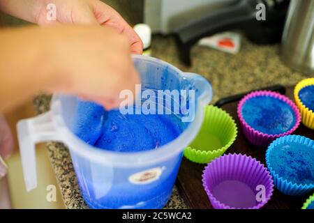 Schmelzen Seife in einem Plastikbecher und Hinzufügen von Farben und Düften vor dem Gießen in bunte Silizium-Formen zu Hause gemacht schmelzen und gießen Seife Stockfoto