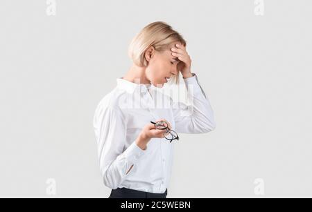 Überarbeiteter Unternehmer, der an Migräne, Müdigkeit oder Problemen auf hellem Hintergrund leidet Stockfoto