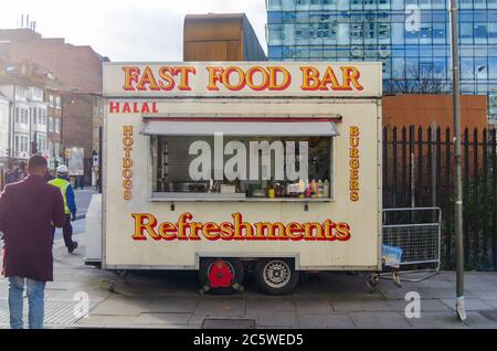 Ein Anhänger mit einer Küche für den Verkauf von Fast Food mit "Fast Food Bar. Erfrischungen. Halal. Burger. Hot Dogs' Zeichen sichtbar, in London Stockfoto