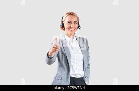 Hotline-Bediener mit Headset, das den Daumen nach oben zeigt, auf hellem Hintergrund Stockfoto
