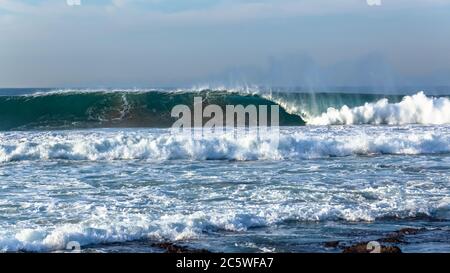 Ocean Wave aufrechte Wand aus blauem und weißem Wasser stürzt auf flachen Riffsandbars . Stockfoto