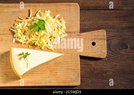 Geriebener Käse und Käse Dreieck mit Petersilie auf Schneidebrett auf Holztisch Stockfoto