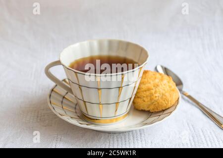 tasse schwarzer Tee mit knusprigen Plätzchen auf weißer Baumwolle Tischdecke Stockfoto