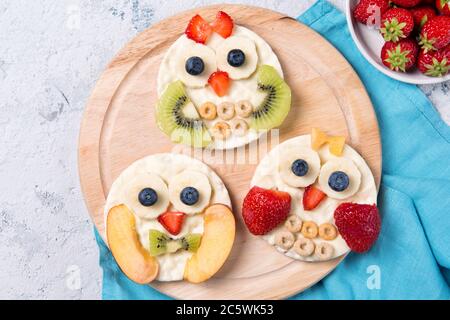 Reiskuchen mit Joghurt und frischem Obst in Formen von niedlichen Eulen auf einem Holzbrett, Mahlzeit für Kinder Idee, Draufsicht Stockfoto