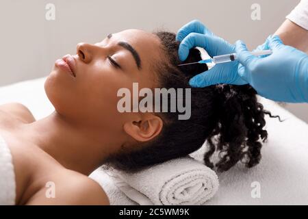 Junge hübsche afrikanische Frau bekommen Haarbehandlung im Spa Stockfoto