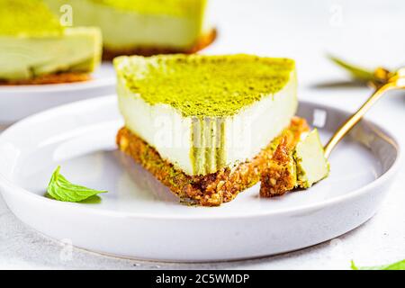 Roher veganer Matcha Käsekuchen auf einem grauen Teller. Stockfoto