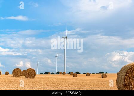 Windkraftanlagen auf einem Getreidefeld in Schleswig-Holstein während der Ernte im Herbst Stockfoto