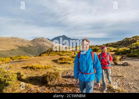 Junges Wanderpaar beim Wandern auf dem Routeburn Track während eines sonnigen Tages. Wanderer tragen Rucksäcke, während sie auf dem Key Summit Track trampeln. Sie sind eingeschaltet Stockfoto