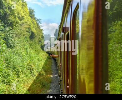 Cranmore, England - Juli 2019: Blick aus dem Fenster eines Dampfzuges auf der East Somerset Railway. Die Leute lehnen sich aus dem Fenster. Stockfoto