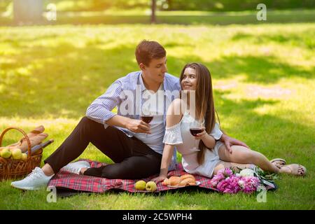 Liebevolles junges Paar feiert Jubiläum mit Wein auf Picknick im Park Stockfoto