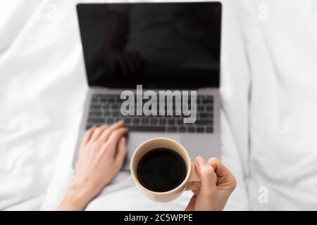 Frau trinkt Kaffee und Networking auf Laptop, pov Stockfoto