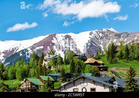 Mount Crested Butte, USA - 20. Juni 2019: Schnee Marooonfarbe Berg im Sommer mit grünen Hügeln und Hügeln Häuser Stadtbild Stadtbild mit Nordic I Stockfoto