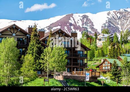 Mount Crested Butte, USA - 20. Juni 2019: Schneebedeckter Berg im Sommer mit grünen Hügeln und Hang Apartment Komplex Ponderosa Wohnanlagen Stockfoto