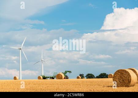 Windkraftanlagen auf einem Getreidefeld in Schleswig-Holstein während der Ernte im Herbst Stockfoto