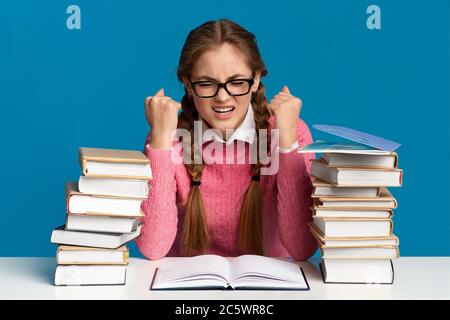 Schweres Studium, viele Aufgaben und Lektionen. Angespanntes Teenager-Mädchen in einer Brille mit Bücherstapeln Stockfoto