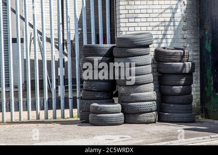 Gebrauchte Autoreifen oder Reifen übereinander gestapelt außerhalb einer Garage oder Werkstatt Stockfoto