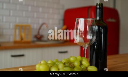 Nahaufnahme einer offenen Flasche Wein und einem Glas Wein mit Obst auf dem Tisch in der Küche. Konzept der Datierung. Stockfoto