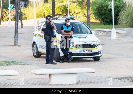 Huelva, Spanien - 4. Juli 2020: Spanische Polizei mit dem Logo der "Lokalpolizei" auf Uniform erhält öffentliche Ordnung an der Strandpromenade von Islantilla Stockfoto