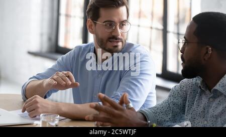 Vertreter mehrerer Rassen und Kunde planen zukünftige Zusammenarbeit während eines formellen Meetings Stockfoto