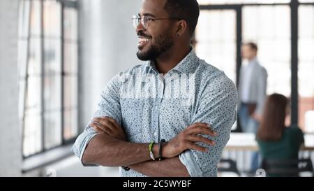 Erfolgreicher afrikanischer Geschäftsmann, der im Büro steht und aus dem Fenster schaut Stockfoto