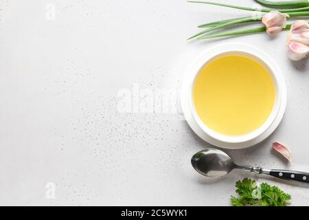 Hühnerbrühe mit Petersilie in Schüssel auf weißem Tisch. Speicherplatz kopieren. Draufsicht. Stockfoto
