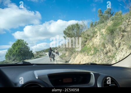 Langsam hinter zwei Wanderradlern auf Landstraße fahren. Manchmal schieben Radfahrer Fahrrad den Berg hinauf Stockfoto