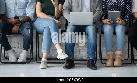 Verschiedene Menschen mit Geräten warten auf Vorstellungsgespräch Turn Stockfoto