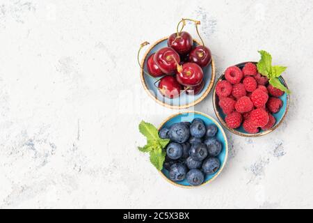 Verschiedene frische saftige Beeren. Kirsche, Heidelbeere und Himbeere in Schalen, Draufsicht Stockfoto