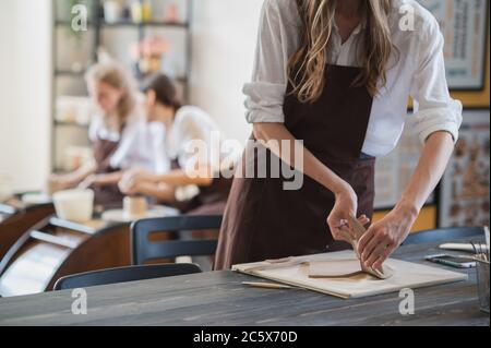 Nahaufnahme von erfahrenen Handwerker Entfernen Teil des Tones während der Herstellung keramischen Produkt in Töpferei Stockfoto