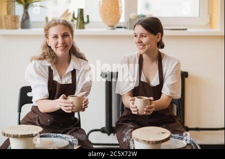 Die weiblichen Töpfer fertig machen eine Tonvase entfernen sie aus dem Töpferrad. Erstellen Vase aus weißem Ton. Herstellung von keramischen Produkten aus weißem Ton Stockfoto