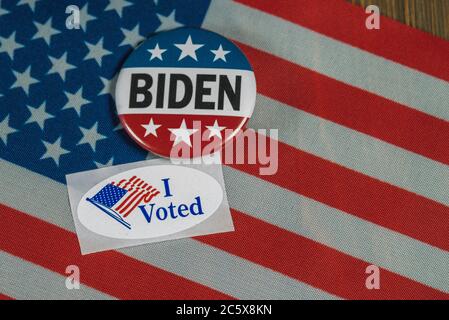 Washington DC - 5. Juli 2020; Runde rot weiß und blau Joe Biden Kampagne Taste neben oval geformt Ich stimmte Aufkleber auf amerikanische Flagge und Holztisch Stockfoto