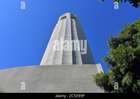 Blick nach oben von der Basis des Coit Tower in Richtung der Spitze an einem klaren Tag mit blauem Himmel und Bäumen. Telegraph Hill, San Francisco, Kalifornien Stockfoto